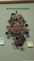 Full view of the handmade metal clock hanging on wall, showing the entire piece with geometric shapes and clock face.