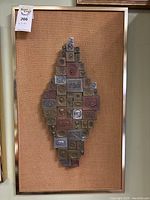 Full front view of metal block collage on burlap and framed.