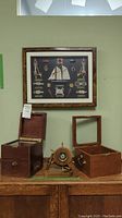 Full view of the nautical knots shadow box mounted on the wall with two wooden display boxes open, and the nautical clock positioned in front.