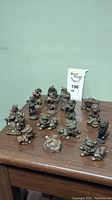 Photo showing 15 brass oriental figurines arranged on wooden surface to show size and variety.
