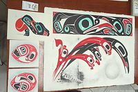 Group shot showing four paper artworks laid out: one long rectangular panel, one large sheet with stylized figures, two circular motif prints