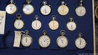 Overview of thirteen stopwatches in blue felt-lined case