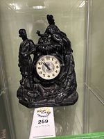 Front view of the black molniya mantel clock depicting man and woman figures and the clock face.