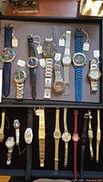 Top view of 10 wristwatches in tray, mixed styles and bands