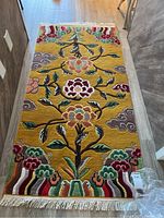 Full view of rug laid on wood floor showing floral pattern and fringe