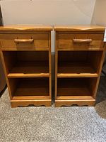 Pair of solid wood bedside tables showing front view with drawer and open shelves.