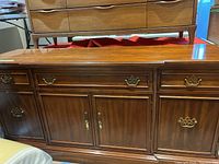 Full front view of wooden buffet cabinet showing all drawers, doors and brass handles.