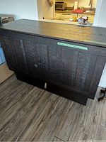 Closed view of dark brown wooden cabinet bed with paneled front