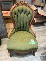 Front view of Victorian carved wood chair with green fabric seat and backrest in a used condition.