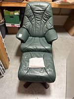 Front view of green leather recliner chair and ottoman in storage area