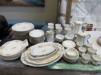 Full overview of all dishware including plates stacked and tea set items arranged in the background