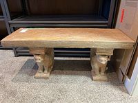 Front view of the concrete garden bench with cat sculpture supports and rectangular top slab.