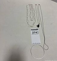 Photo of all jewelry pieces laid out on a surface, displaying the necklaces, ring, and bangle.