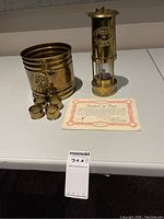 Lamp, bucket, four napkin rings and certificate displayed on table