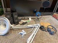 Monitor, speakers, microphone, headphones, and desk lamp displayed on carpet