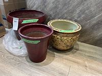 Three plant pots displayed on floor: two red/burgundy pots and one Asian-patterned pot, showing overall lot contents and size.