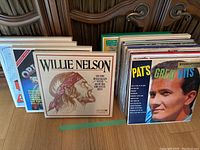 Vinyl records in cardboard sleeves arranged in rows showing front covers of Willie Nelson Greatest Hits, Pat Boone Great Hits, others.