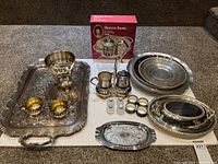 Overall view of all silverplated serveware pieces including trays, ice bucket, bowls, cruet set, shakers, napkin rings and boxed item