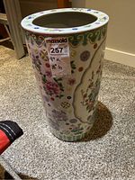 Front side view of the tall ceramic vessel showing colorful floral and ornamental patterns on a white base.