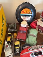 Tire-shaped Hot Wheels 12-car carrying case with several larger toy vehicles in front