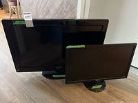 Front view of Panasonic 32 inch TV and ASUS 24 inch monitor side by side on floor