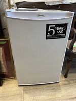 Exterior view of white Danby upright freezer with 5-year warranty label