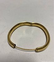 Yellow gold plated or gold filled etched bracelet shown open, highlighting hinged mechanism and wire clasp.