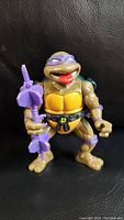 Front view of Donatello action figure with purple staff and yellow shell chest.