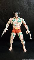 Front view of the 1992 Wolverine Weapon X figure showing green circuitry tattoo details on chest and arms, brown shorts, and extended claws on both hands.