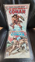Photo showing two vintage Savage Sword of Conan comic issues, one with Conan holding shield and sword, the other with Conan fighting two characters.