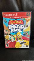 Front cover of The Simpsons Road Rage PlayStation 2 game case showing main characters in animated style driving cars.