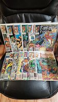 Thirteen Fantastic Four comic books arranged on a chair, showing variety of covers and issues including #308 and #320.