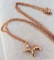 Photo showing the full gold-plated balloon dog pendant attached to the chain with the clasp visible.