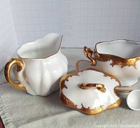 Full set showing lidded sugar bowl, creamer, tray, and spoon with gold decoration