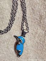 Close-up of hummingbird pendant with blue and metallic enamels on silver, showing front details of the bird pendant and chain.