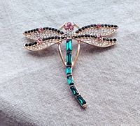 Front view of a large dragonfly brooch with gold-tone metal and colorful gemstones on wings and body.