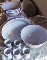 Top view showing two large white cereal bowls, four smaller cereal bowls stacked, and four egg cups arranged in front, all white with a smooth glossy finish.