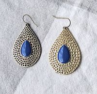 Front view of vintage sterling silver drop earrings with teardrop-shaped lapis stones and hammered textured surface.