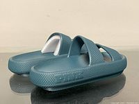 Side and top angle view of greenish-blue slip-on sandals showing 'Pink' embossed branding on side and overall style.