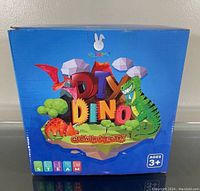 Front view of the blue box featuring colorful dinosaur illustrations and the product name 'DIY Dino Glow in the Dark'.
