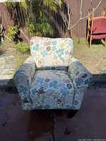 Front view of upholstered armchair with floral pattern and visible wooden legs.