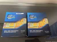 Two Intel Xeon Processor E5-2670 CPUs in original blue retail boxes with Intel Xeon logos and chipset design, stacked side by side.