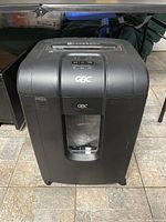 Front view of a black GBC paper shredder SX19-09, showing the control panel and the transparent waste bin window.