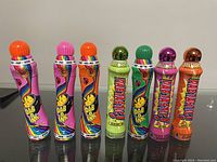Photo of 7 DaboInk bingo markers in a row showing colorful tops and labels with different names and scents.