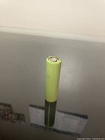 Full view of cylindrical Panasonic lithium-ion battery standing upright on reflective surface.