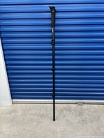Full length view of black Benro monopod against a blue corrugated door.