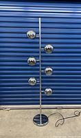 Full view of chrome floor lamp showing six spherical heads mounted on a central pole with round base