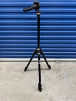 Full view of black aluminum Manfrotto tripod with legs extended and trigger head shown upright.