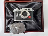 Camera and strap inside wooden box with black satin lining