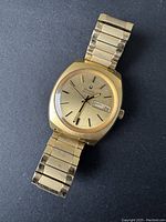 Full front view of watch with bracelet laid flat on dark surface